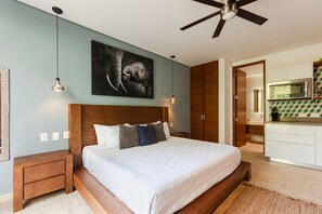 A bedroom with a large bed, wooden headboard, and a ceiling fan. There is a kitchen visible through an open door. - Room fully equipped Spa and gym free (Tulum)