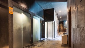 Un couloir doté d’un sol carrelé, de portes en verre et d’un ascenseur en métal.