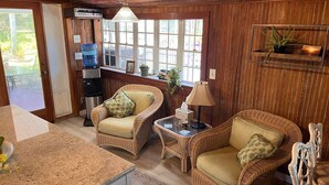 A cozy room with wicker furniture, a water dispenser, and a window with a view.