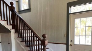 A wooden staircase with a handrail, a door with a window, and a rug on the floor.