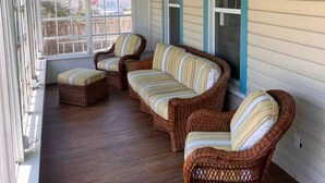 A covered porch with wicker furniture and a view of the backyard.