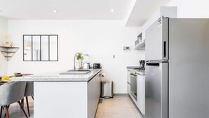 Ett modernt kök med en central köksö, vitvaror i rostfritt stål och en minimalistisk design.