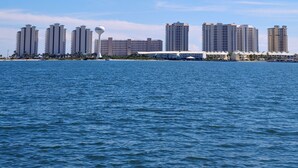 Een uitzicht op het water met een stadsbeeld, hoge gebouwen, een jachthaven en een helderblauwe lucht.