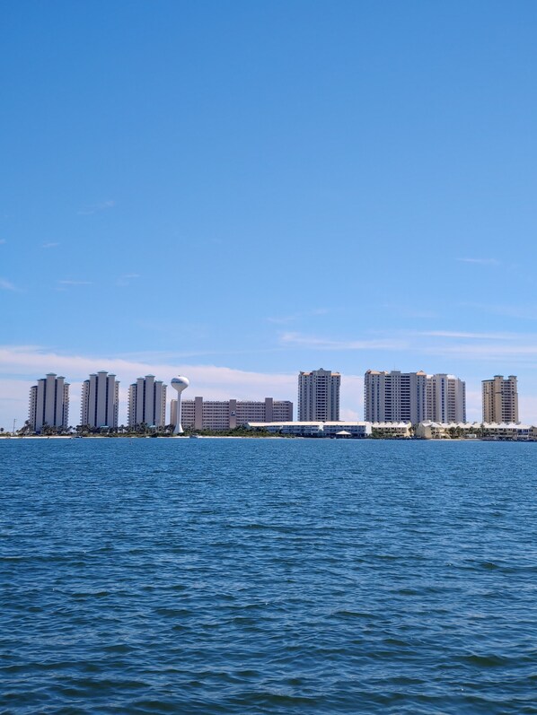 Blick auf eine Stadt am Wasser mit Hochhäusern, einem Yachthafen und blauem Himmel.