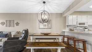 Un salon moderne avec un canapé en cuir, une table à manger en bois et un lustre.