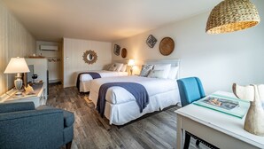 Une chambre d’hôtel avec deux lits, un bureau, une chaise et un luminaire suspendu.