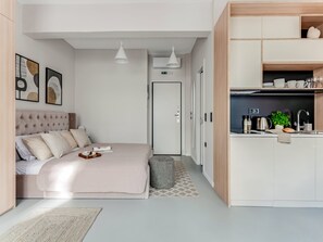Una habitación de hotel moderna con cama, mesita de noche y una pequeña cocina.
