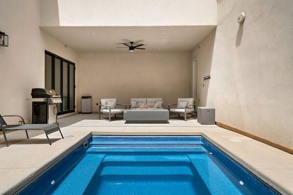 Une piscine avec un ventilateur de plafond, un ensemble de canapés et une petite table dans une pièce baignée de lumière.
