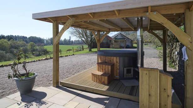 Ein Bereich mit Holztonnen-Whirlpool, einer Holzterrasse und einem Blumentopf.