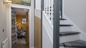 Eine Treppe mit gemusterten Teppichstufen, Holzdielen und einer Tür zu einem Raum mit einem gemusterten Vorhang.