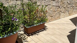 Un muro in pietra con due fioriere rettangolari su un patio piastrellato.