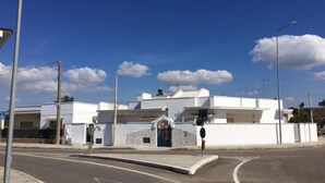 Un edificio moderno con facciata bianca, ingresso curvo e cielo sereno.