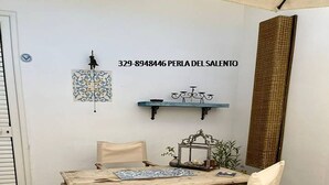 Zona pranzo con tavolo in legno rustico e quattro sedie, un appendiabiti decorativo e una piccola mensola con un modellino di bicicletta.
