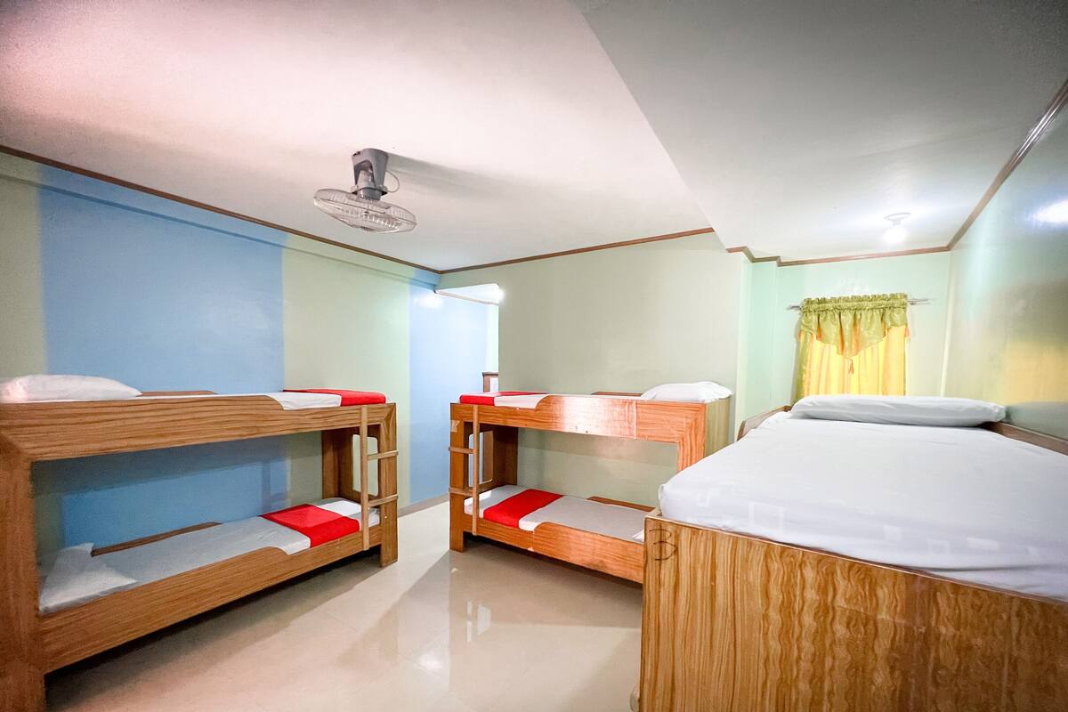 Ein Zimmer mit Etagenbetten, einem Deckenventilator und einem Fenster mit Vorhängen.