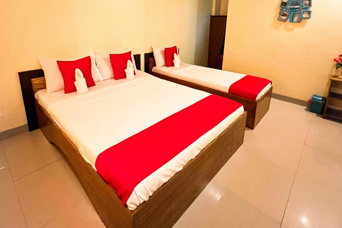 Ein Hotelzimmer mit zwei Betten, einem Holzkopfstück, einer roten und weißen Bettdecke und einer Wanddekoration.