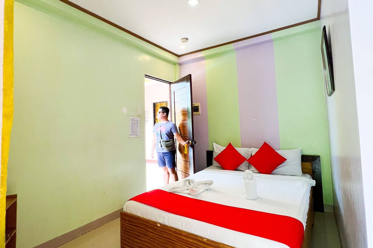 Ein Hotelzimmer mit einem großen Bett, einem Holzkopfstück und einer rot-weißen Bettdecke.