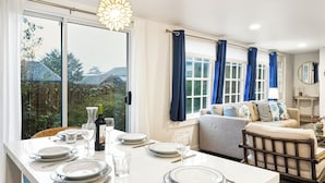 Un comedor con una mesa dispuesta para cuatro personas, un sofá y vistas al exterior.