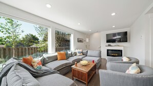 A modern living room with grey sofas, a wooden coffee table, and a fireplace.