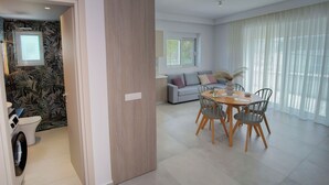 Una sala de estar moderna con comedor, un sofá y una ventana con cortinas.