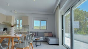 Una cocina moderna con armarios blancos, una mesa de comedor con sillas y vistas al exterior a través de amplios ventanales.