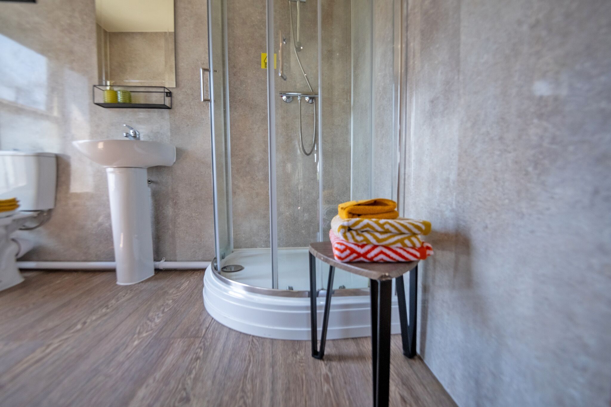 A modern bathroom with a glass-enclosed shower, a sink, and a toilet.