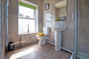 A bathroom with a toilet, sink, and window. - Waterfall Country Escape (Neath)