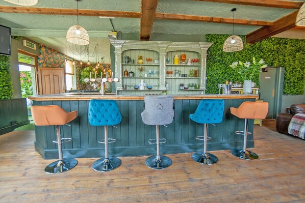A bar area with four stools, a counter, and a green wall with a plant. - Waterfall Country Escape (Neath)