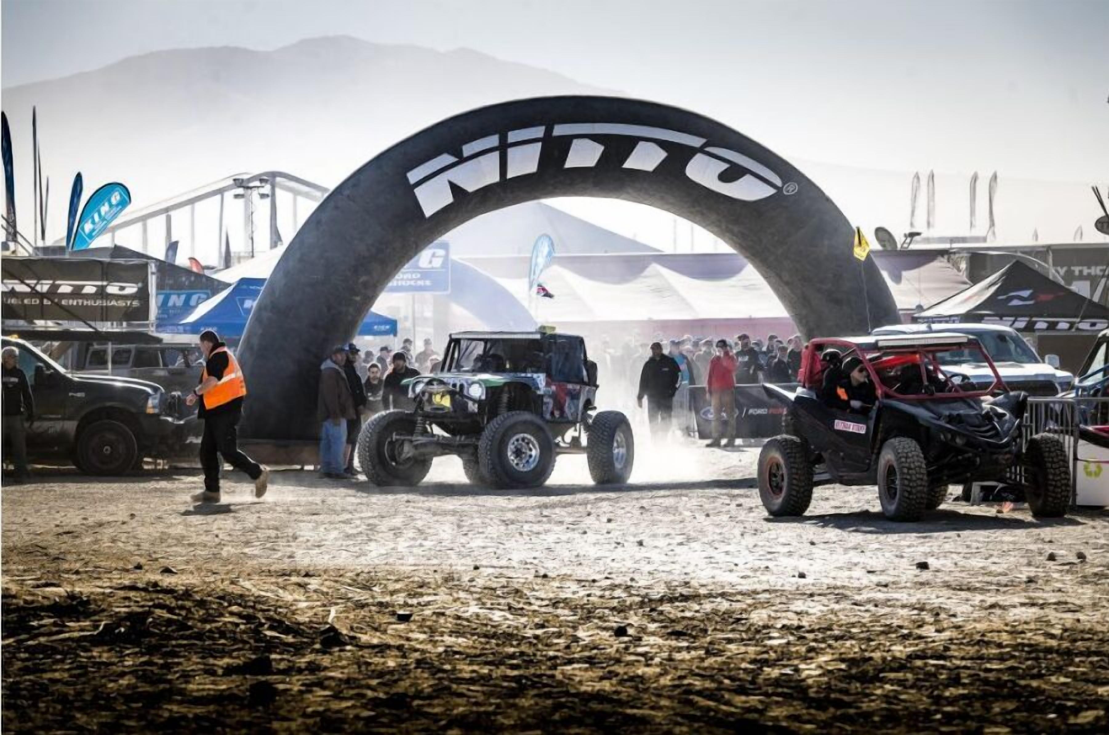 A dirt track event with vehicles and spectators.