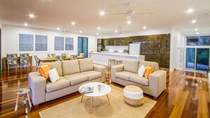 A modern living room with a sofa set, a coffee table, and a dining area with a kitchen in the background. - Finding Solace - Sunrise at 1770 (Agnes Water)