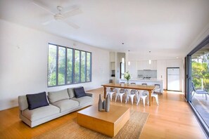 A modern living room with a sofa, coffee table, and dining area with chairs.