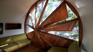 Ein Zimmer mit einem großen, runden Holzhaufenster, einem grünen Sofa und Holzdielen.