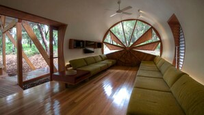 Ein modernes Interieur mit Holzboden, einem Ecksofa, einem Flachbildfernseher und großen Fenstern.
