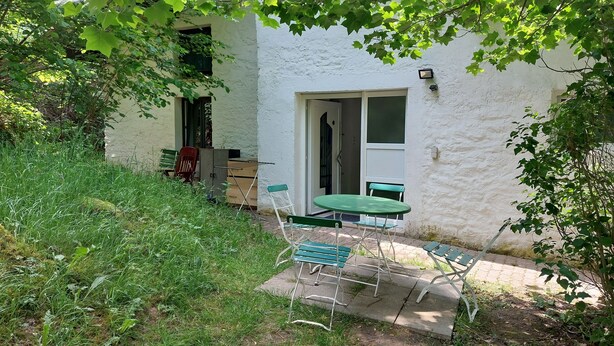 A small outdoor patio area with a table and chairs, a door, and a window.