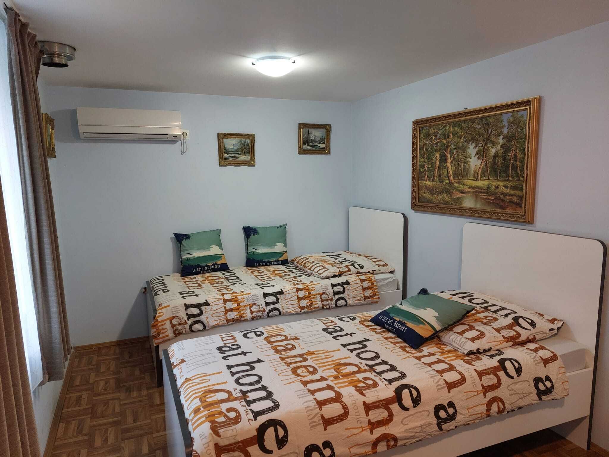 Ein Schlafzimmer mit zwei Betten, einem Deckenventilator, einer Klimaanlage und einem Bild an der Wand.