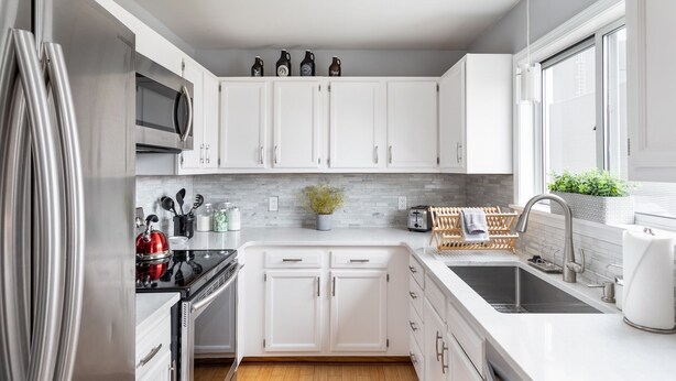 A modern kitchen with white cabinets, stainless steel appliances, and a window with a view. - Your Up North Getaway! (Traverse City)