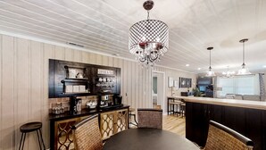 Une cuisine moderne dotée d’un coin bar, comprenant un lustre, des tabourets de bar et un espace dédié au café et au thé.