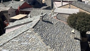 Una cittadina costiera con strade acciottolate e edifici, un cielo azzurro limpido e vista sul mare.