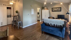 A spacious living area with a blue sofa, wooden flooring, a kitchenette, and a dining area. - Quiet & Cozy Pet-Friendly Condo with Pool & Garage  (Bettendorf)