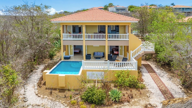 A two-story building with a pool, outdoor seating, and a staircase leading to a balcony. - Holiday Home Gran Veranda with private pool and ocean view, Coral Estate (Willemstad, Curacao, Curacao, Caribbean)