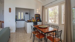 A compact kitchen with a dining area, a built-in microwave, and a window with blinds. - Holiday Home Gran Veranda with private pool and ocean view, Coral Estate (Willemstad, Curacao, Curacao, Caribbean)