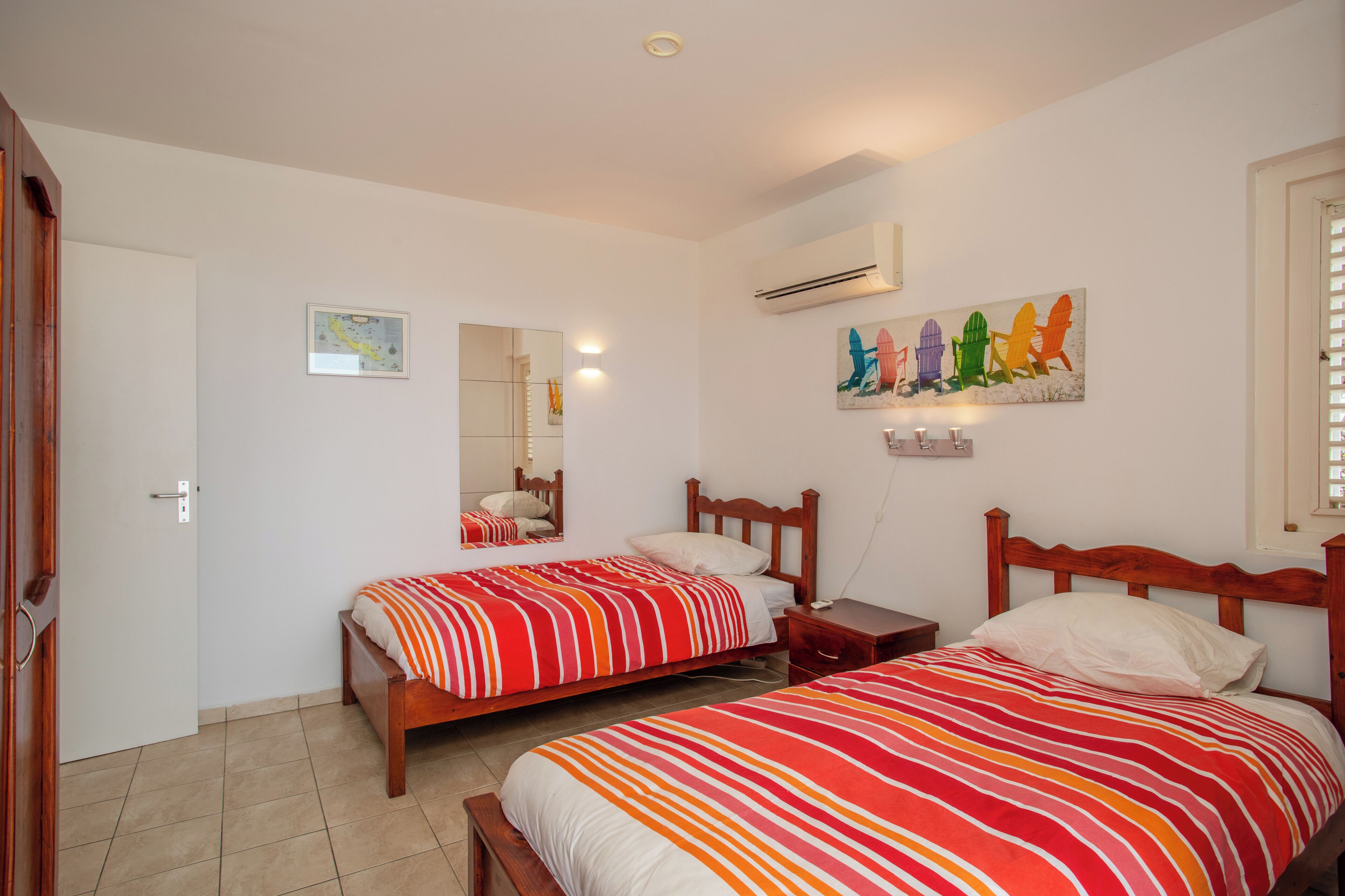 A bedroom with two beds, a mirror, an air conditioner, and a painting on the wall.