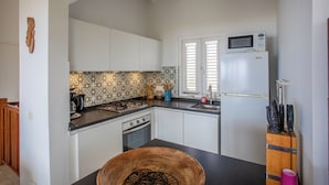 A kitchen with white cabinets, a patterned backsplash, a microwave, a stove, and a sink. - Holiday Home Gran Veranda with private pool and ocean view, Coral Estate (Willemstad, Curacao, Curacao, Caribbean)