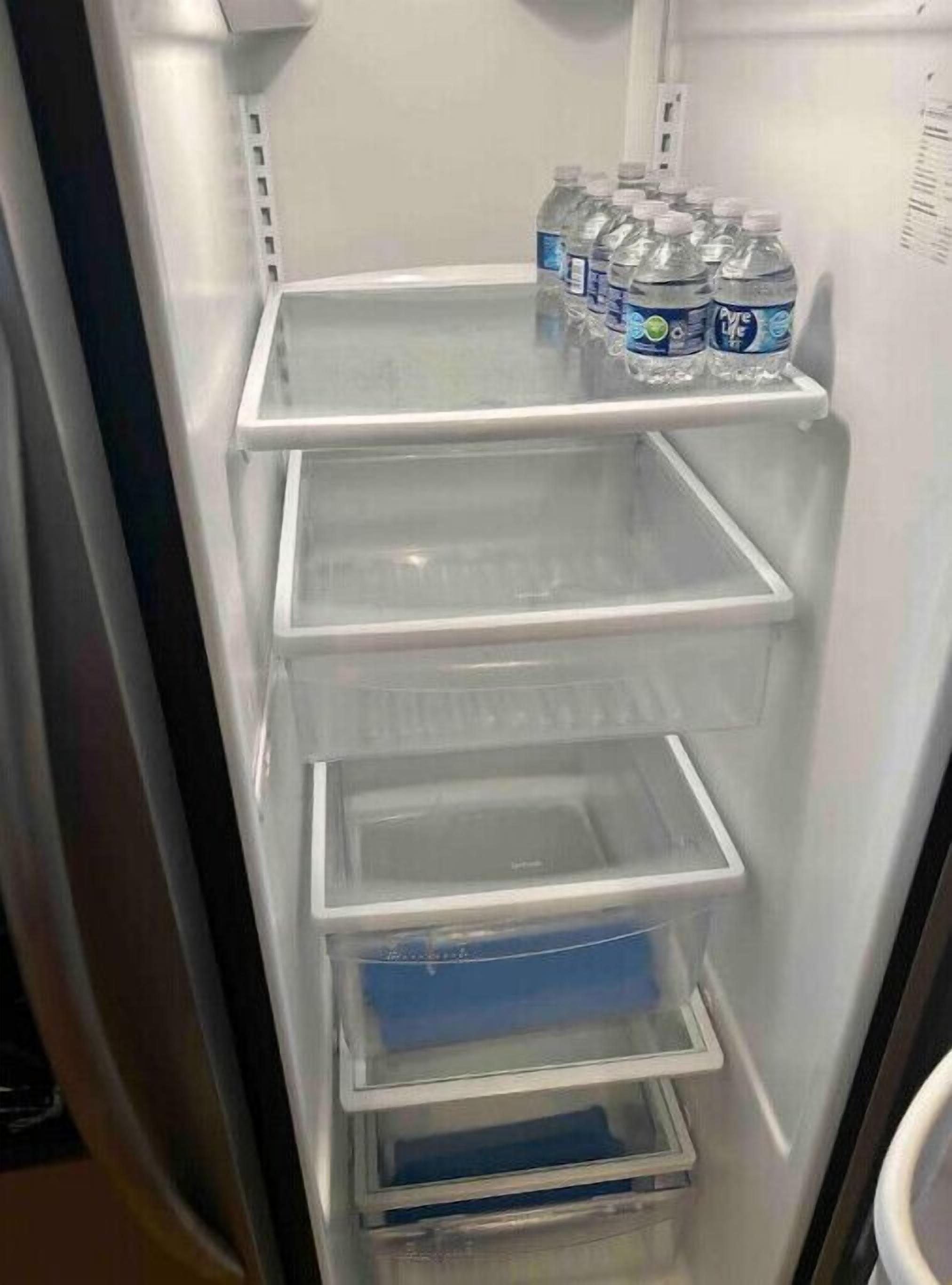 An empty refrigerator with multiple shelves and a freezer compartment.