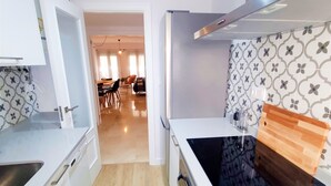Een moderne keuken met witte kasten, een zwart fornuis en een houten snijplank.