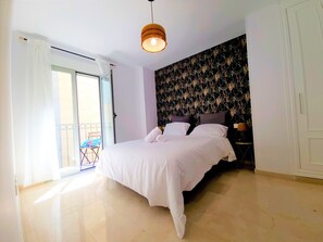 Un dormitorio con cama, luz de techo, ventana con cortinas y balcón.