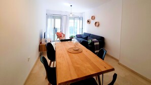 Een eetruimte met een houten tafel, zwarte stoelen, een klein bijzettafeltje met een laptop en een glazen koepel als middelpunt.
