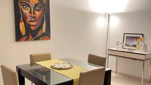 A dining area with a table, chairs, a painting, a desk with a computer, and a floor lamp. - Relaxing 2 Bed Apartment With Pool View Sol Dunas (Sal)