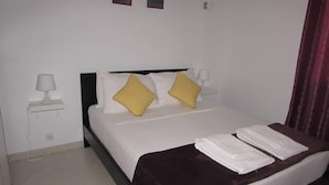 Una camera d'albergo con un letto, due abat-jour, un comodino e due quadri appesi al muro.
