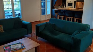 A modern living room with a green sofa, a wooden coffee table, and a kitchen in the background. - Villa Marina , vue sur le Canal, à 5 Minutes du Centre Historique (Aigues-Mortes)