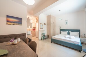 A modern bedroom with a bed, a sofa, a dining table, and a kitchen area. - Cozy Acropolis Studio by Cloudkeys (Athens)